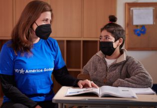 Niño sonriendo y mujer de fundación en Chile - América Solidaria